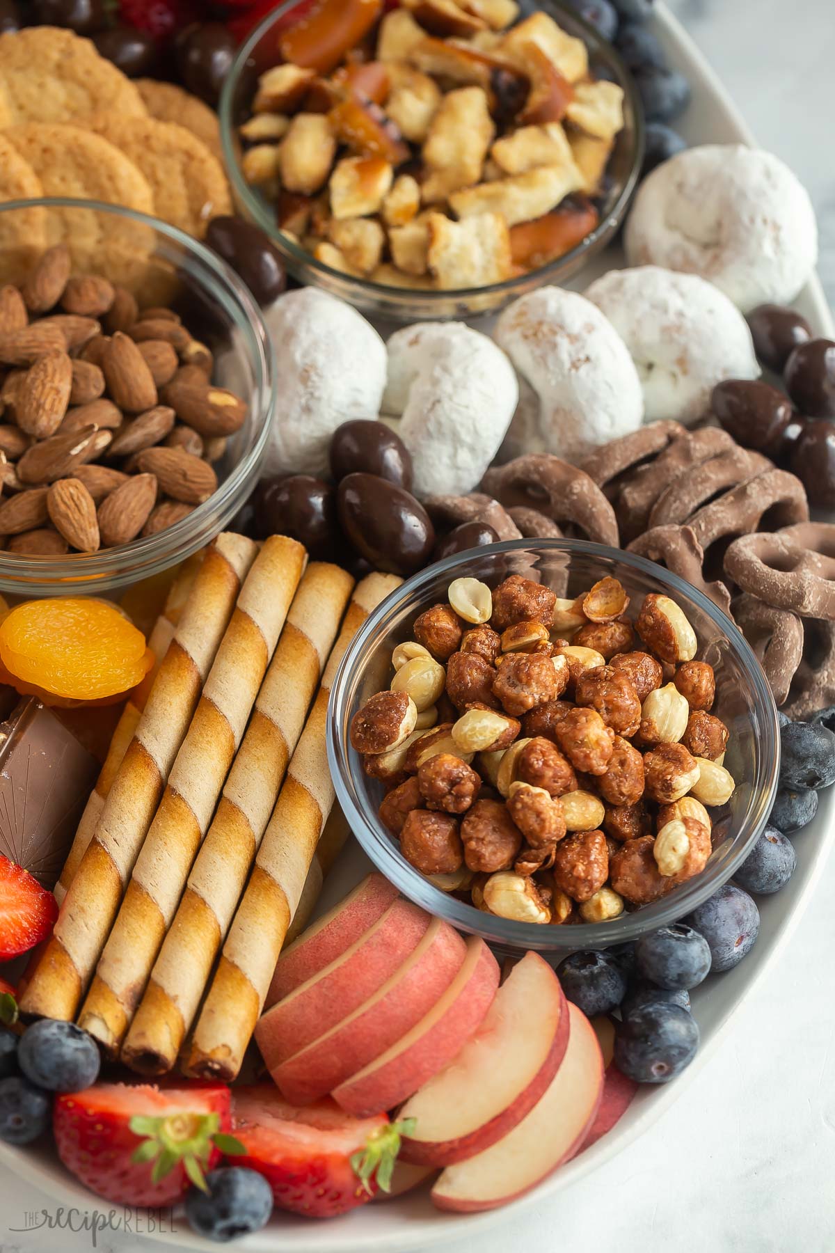 close up image of dessert board with cookies nuts and fruit.