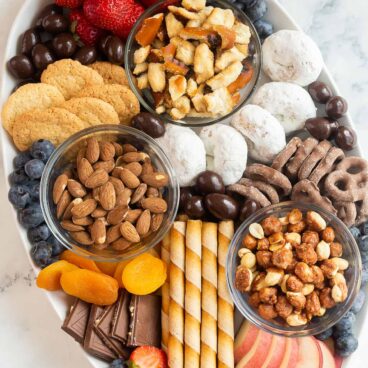 overhead image of dessert charcuterie board with cookies chocolates nuts and fruit.