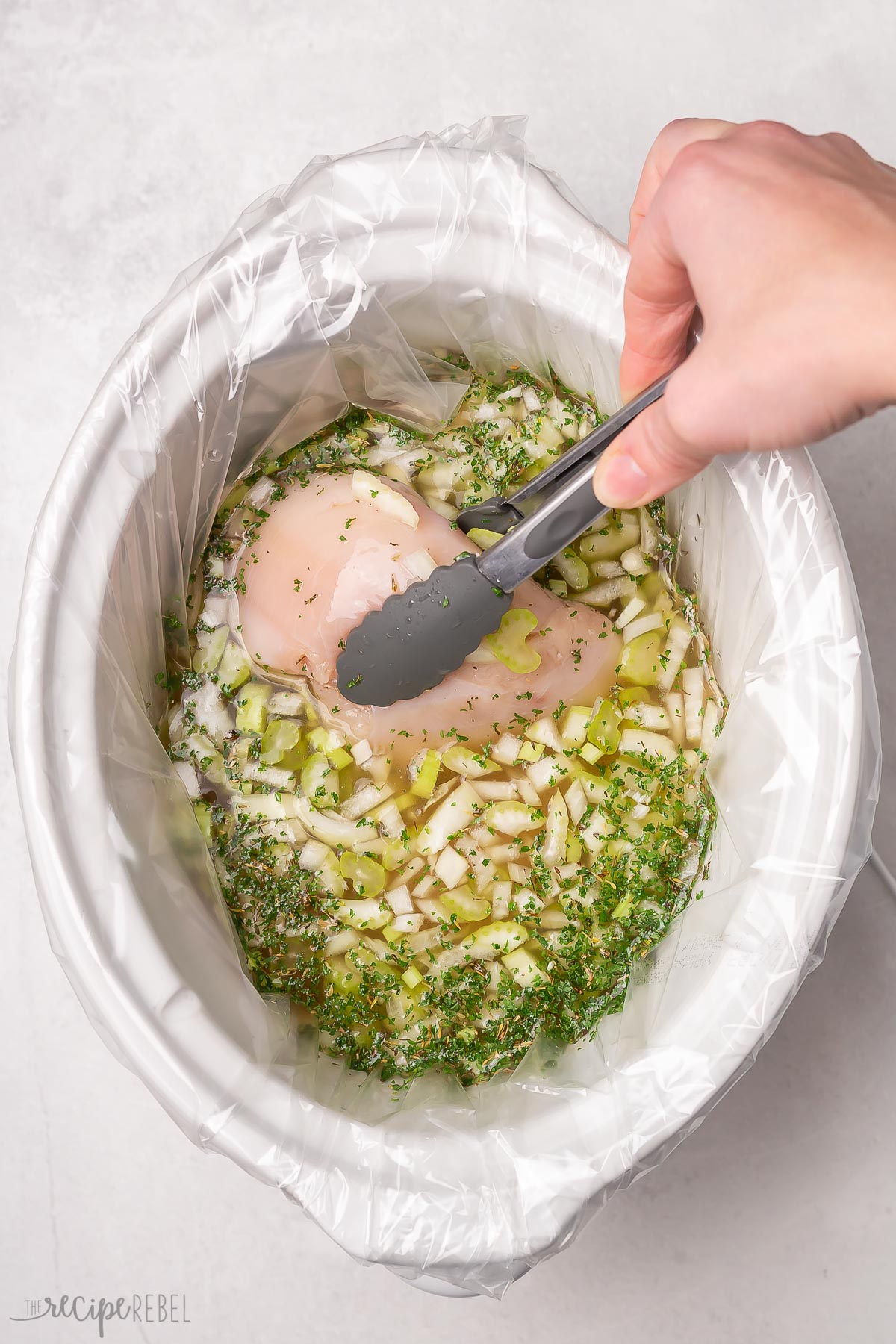 chicken breasts being added to broth in slow cooker.