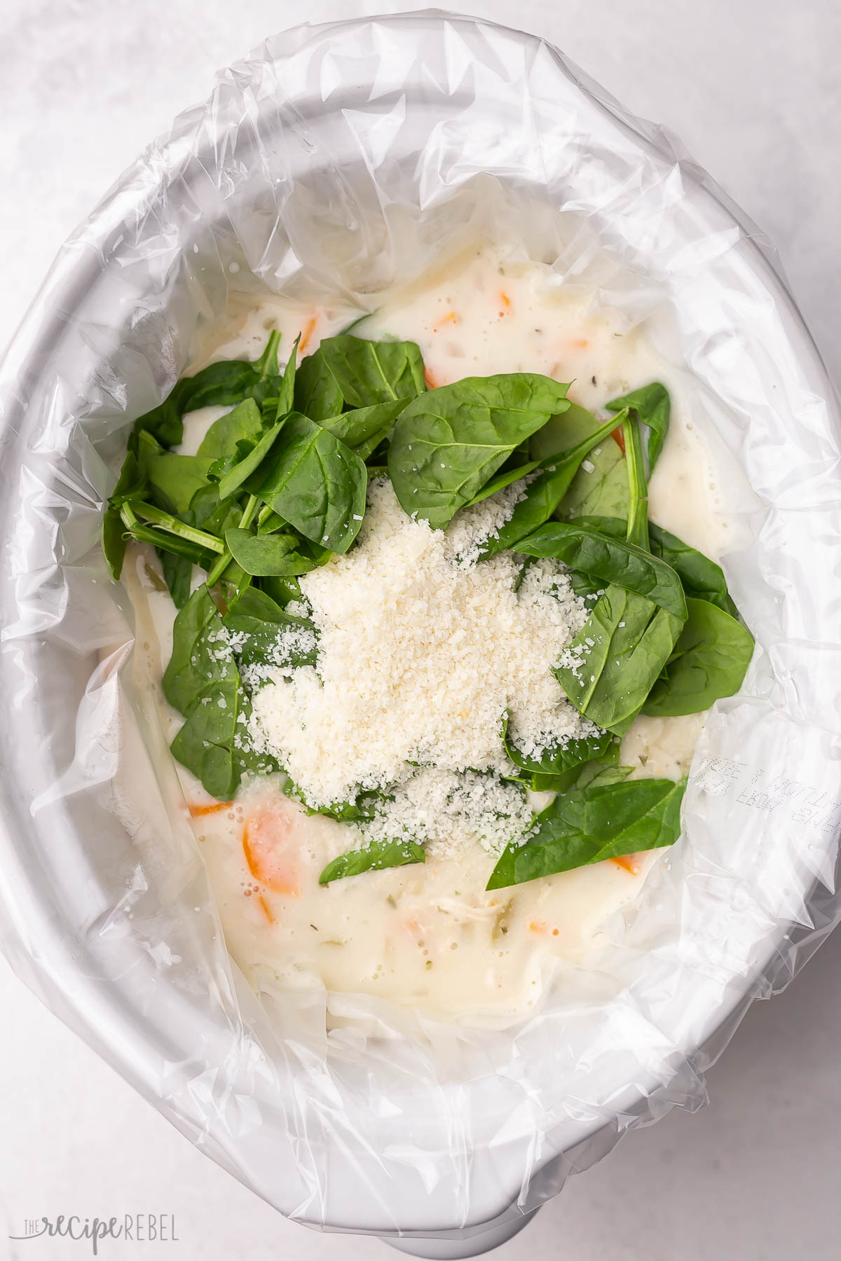 spinach and parmesan added to chicken gnocchi soup in slow cooker.