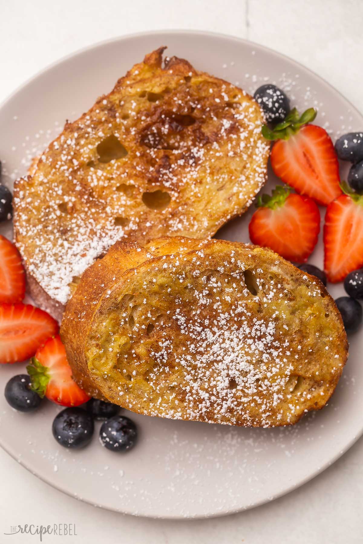 Top view of french toast on plate with blueberries and strawberries.