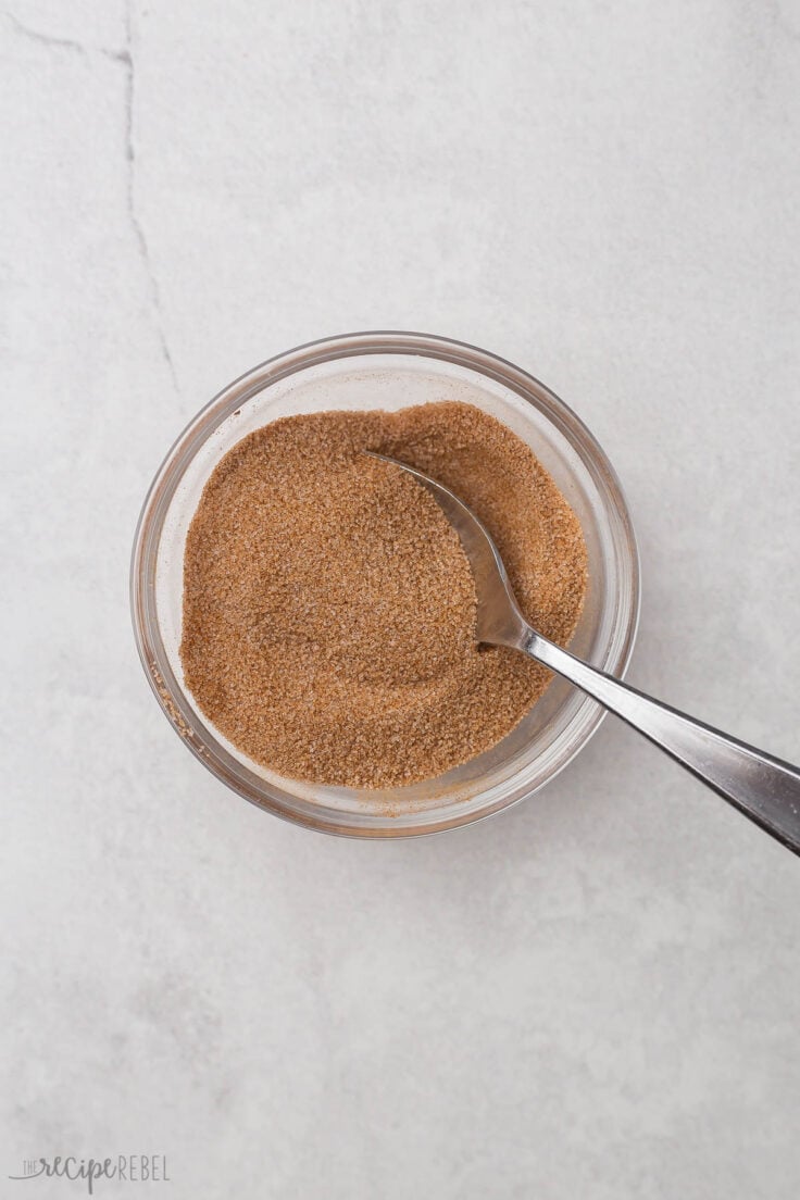a glass bowl filled with stirred cinnamon and sugar.
