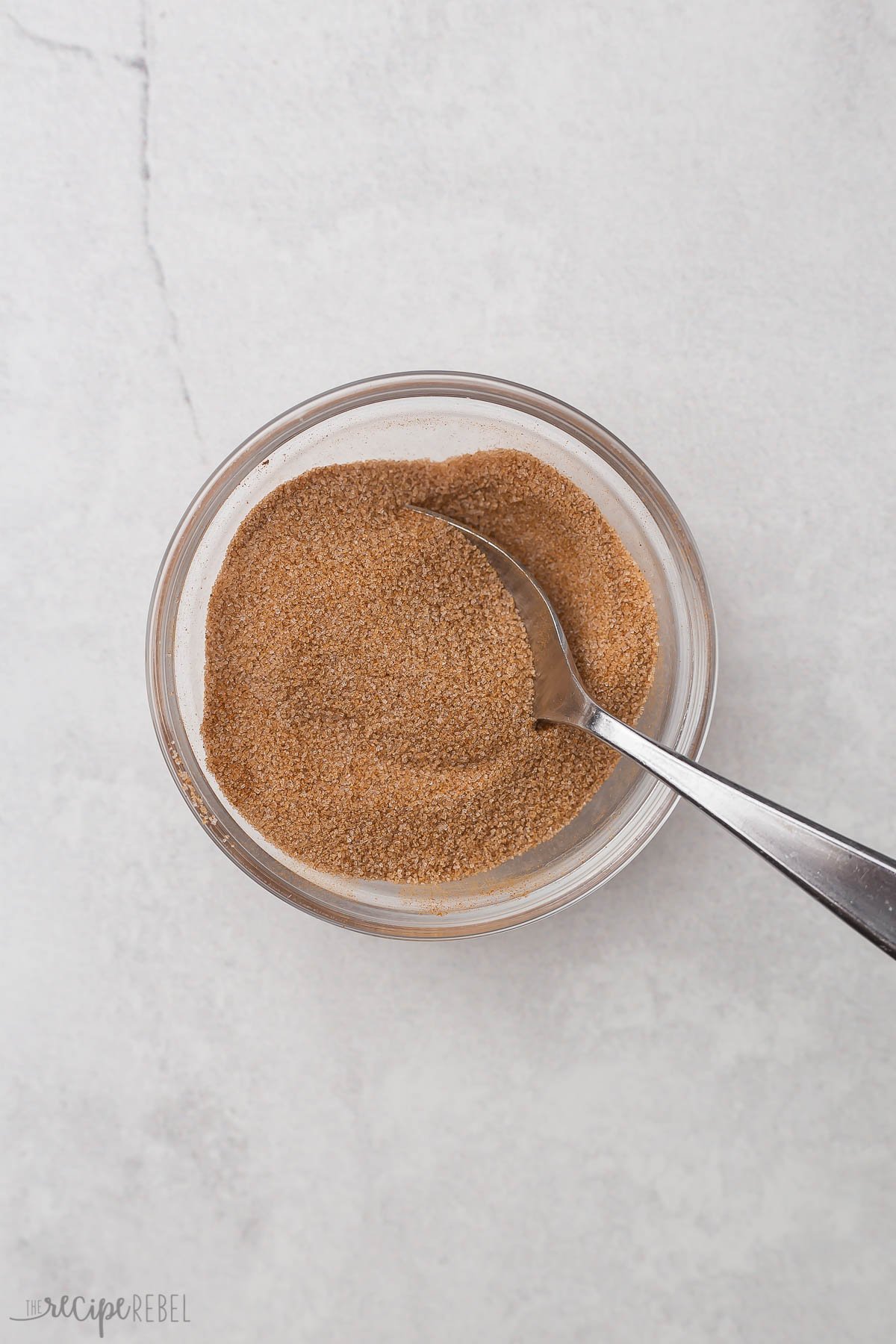 a glass bowl filled with stirred cinnamon and sugar.