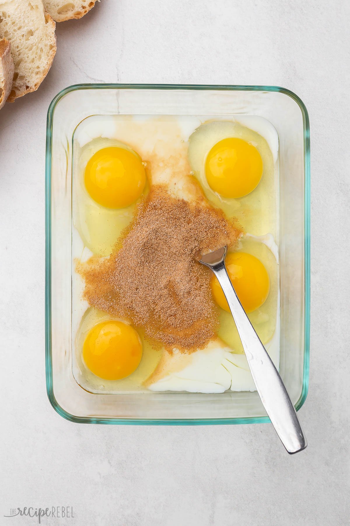 a glass dish filled with unmixed eggs, milk, and cinnamon sugar mixture.