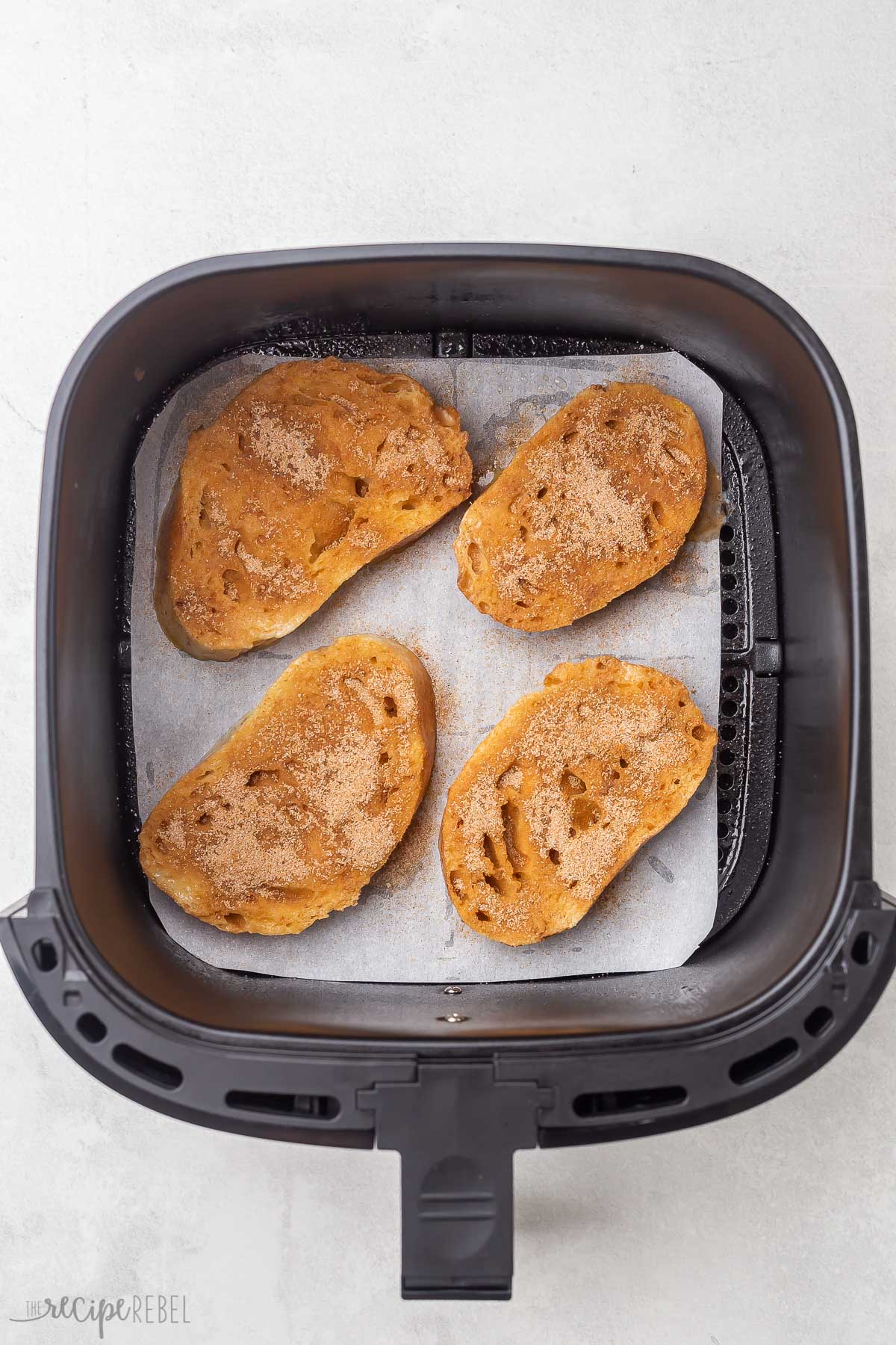 overhead view of golden french toast in black air fryer basket.