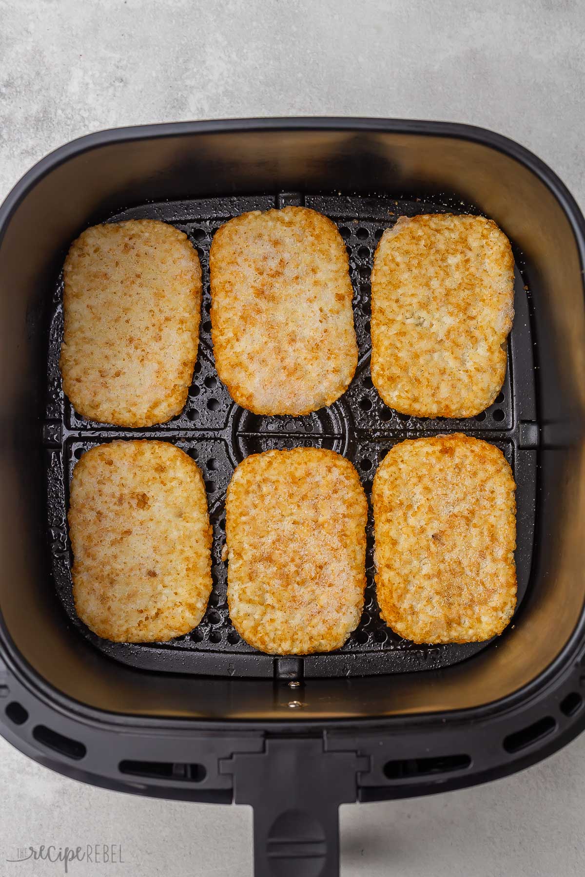 top view of fried hash brown patties lying in air fryer basket