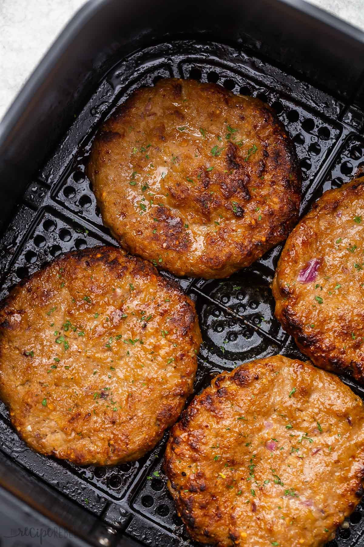 cooked turkey burger patties in black air fryer basket