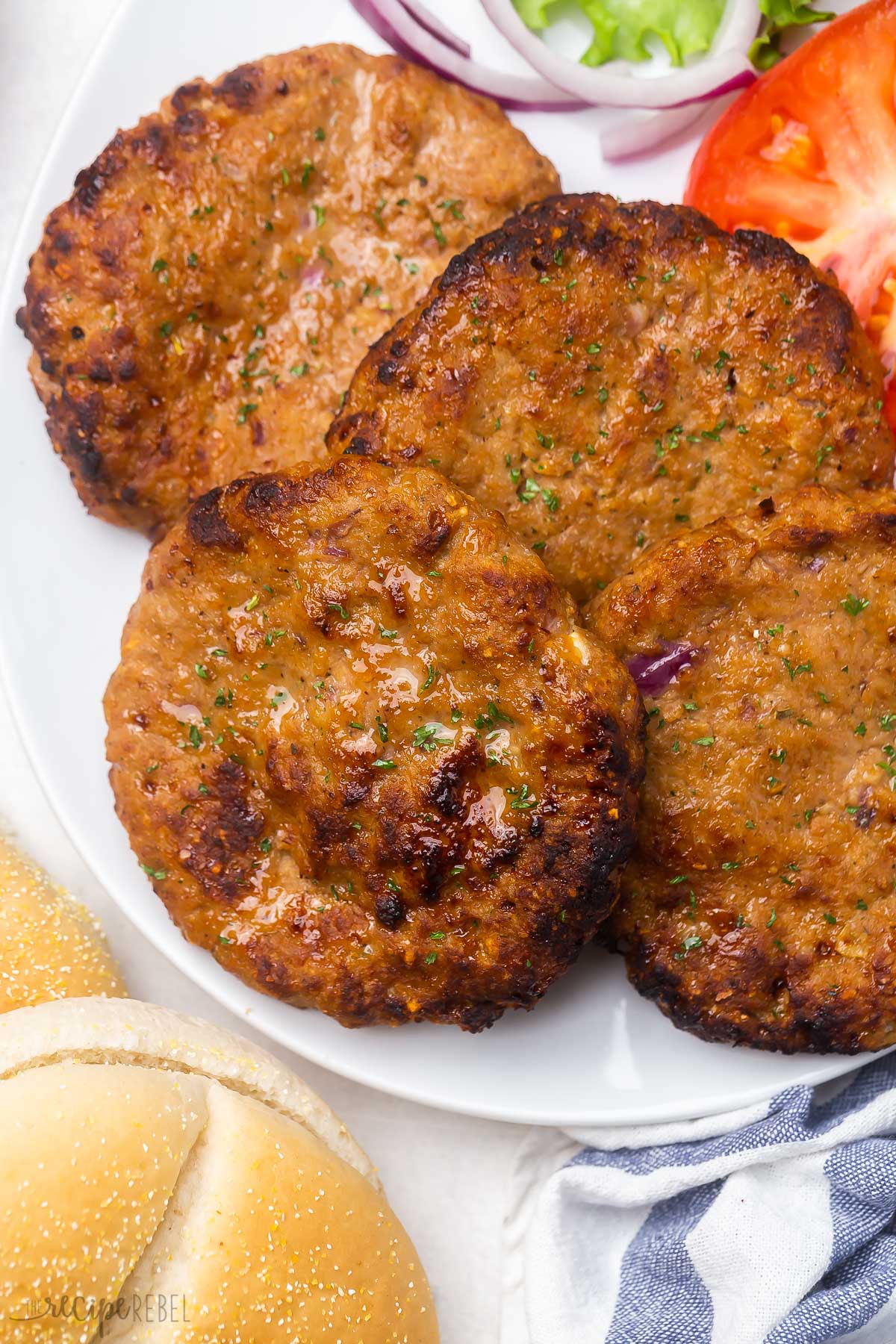 overhead view of fried turkey burgers on white plate with toppings beside.