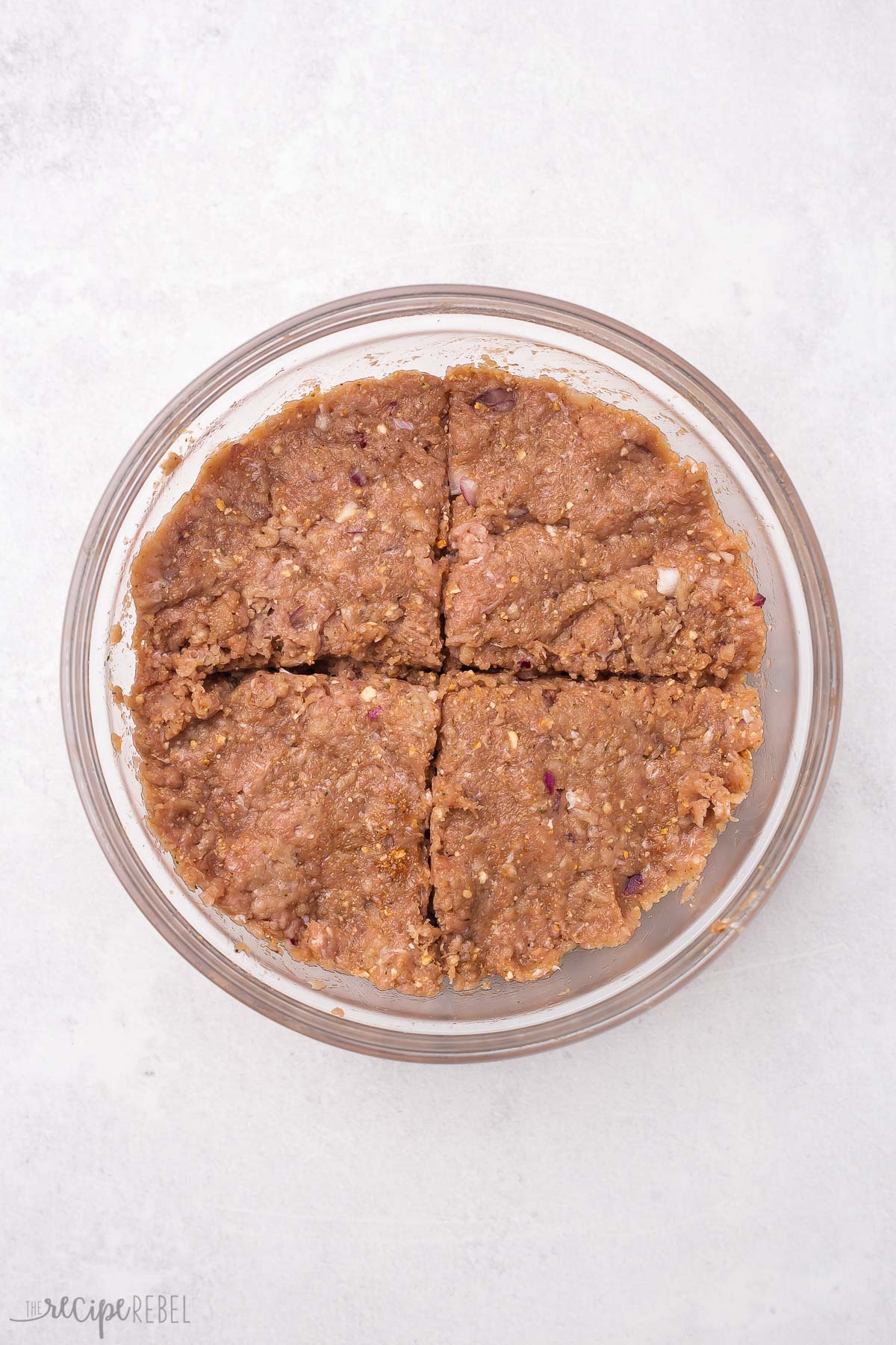 mixed turkey burger ingredients in glass bowl divided into quarters.