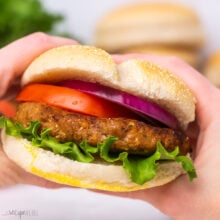 close up of turkey burger topped with lettuce, tomato, and red onion.