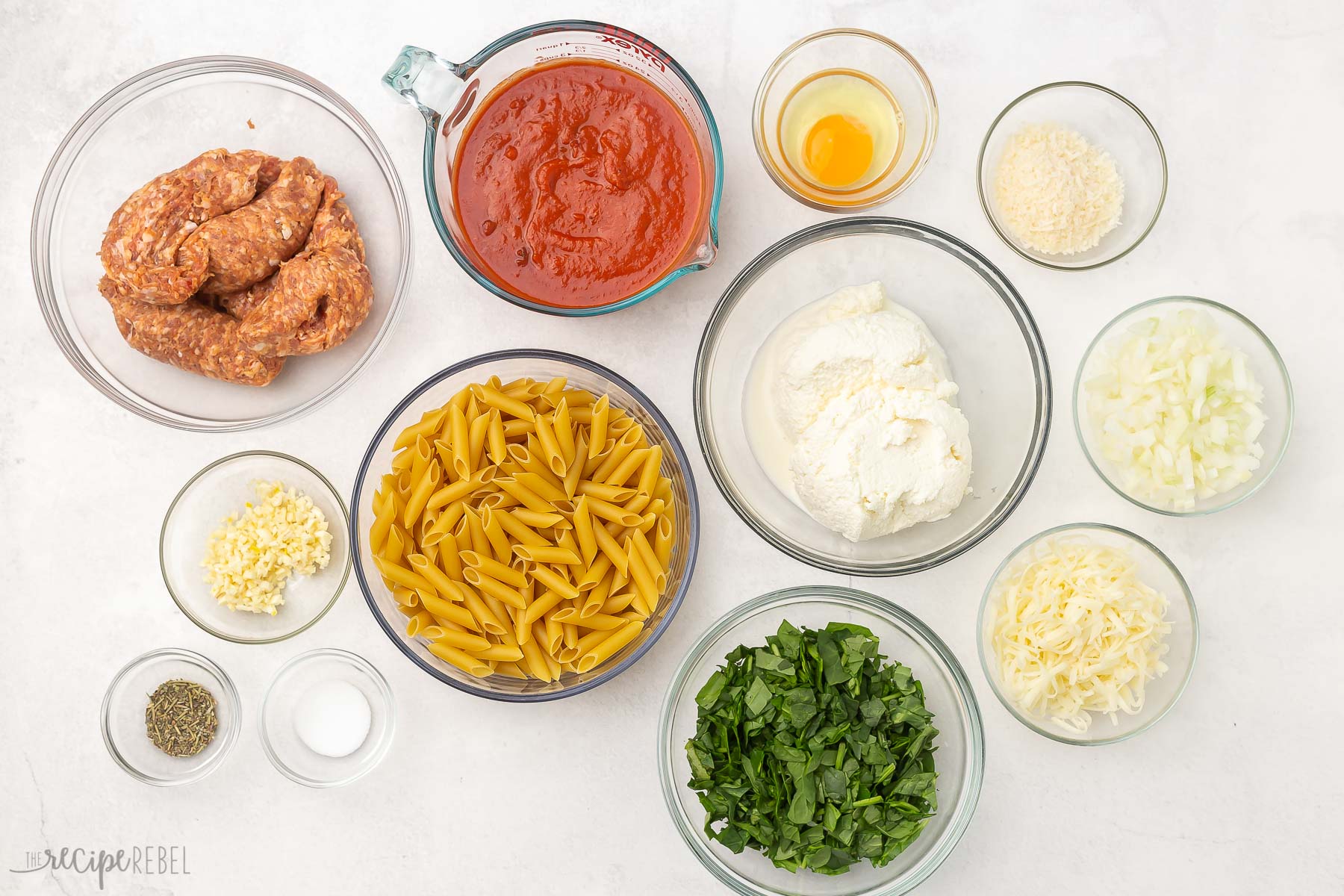 overhead view of bake mostaccioli pasta ingredients in glass bowls.