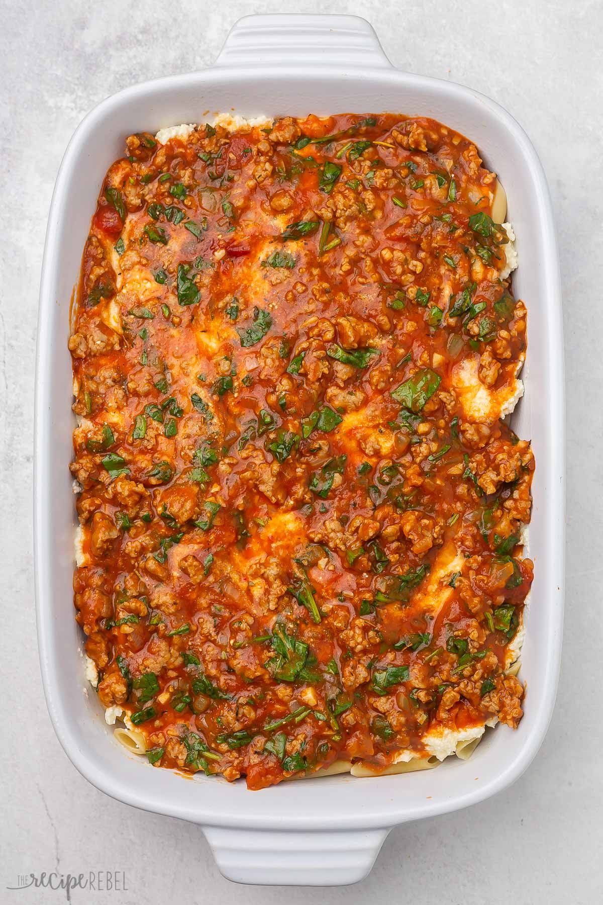 baked mostaccioli pasta assembled in a white dish.