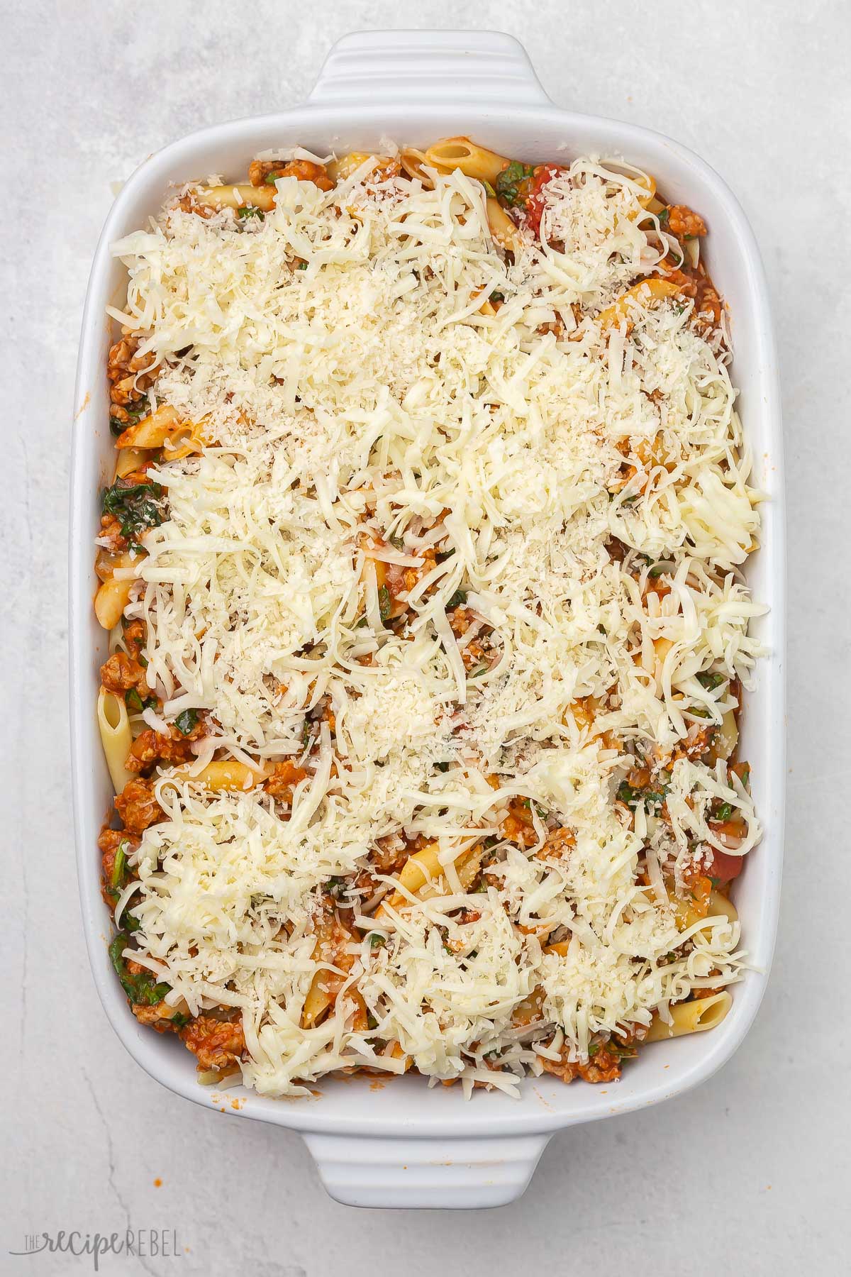 top view of baked mostaccioli pasta with shredded cheese on top.