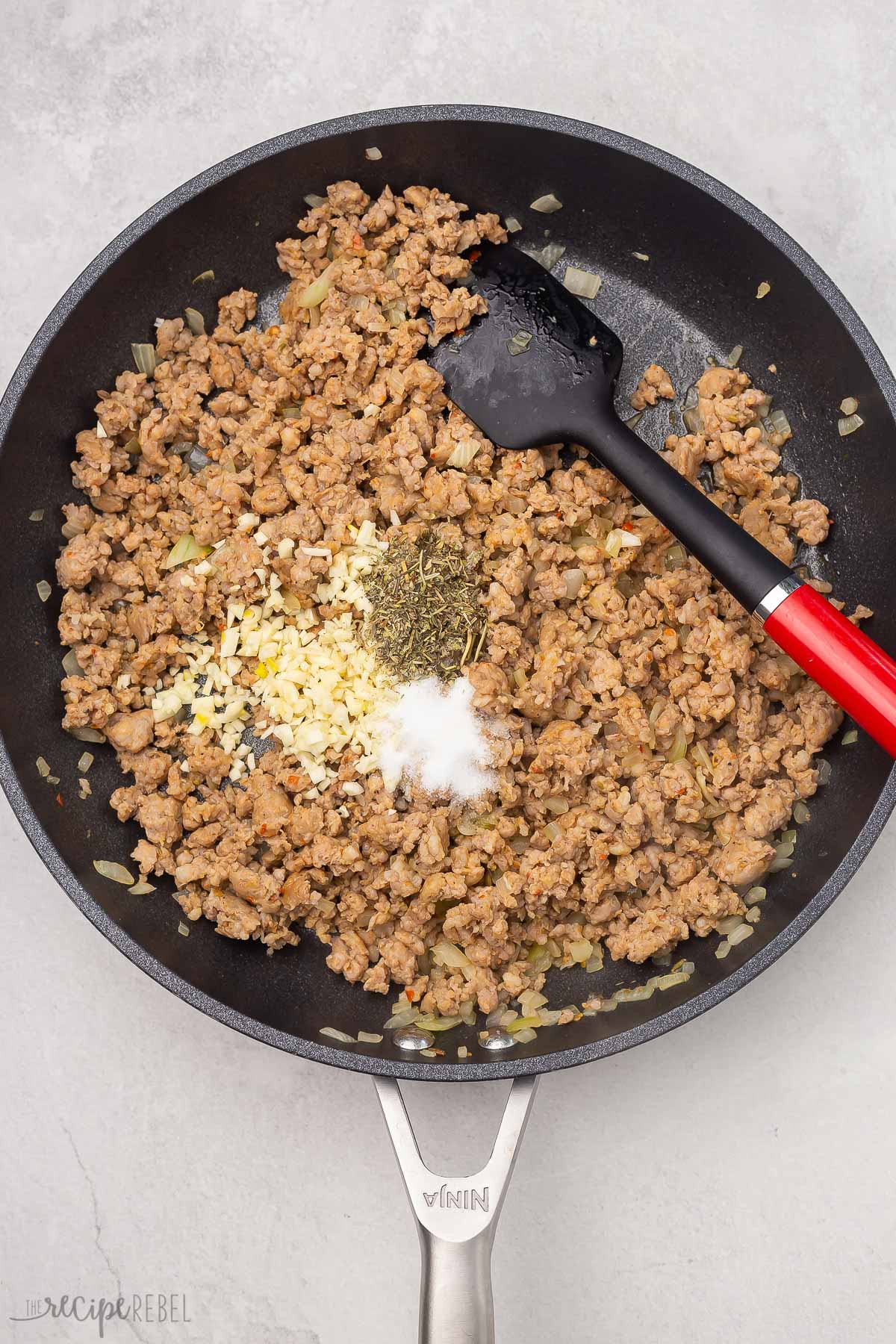 fried ground meat in a black frying pan with spices on top.