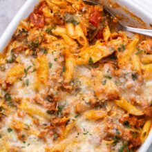 close up of serving spoon lying in pan of baked mostaccioli pasta.