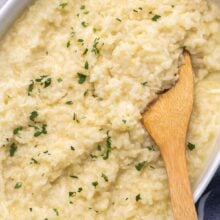 Top view of baked risotto in a casserole dish with a wooden spoon in it.