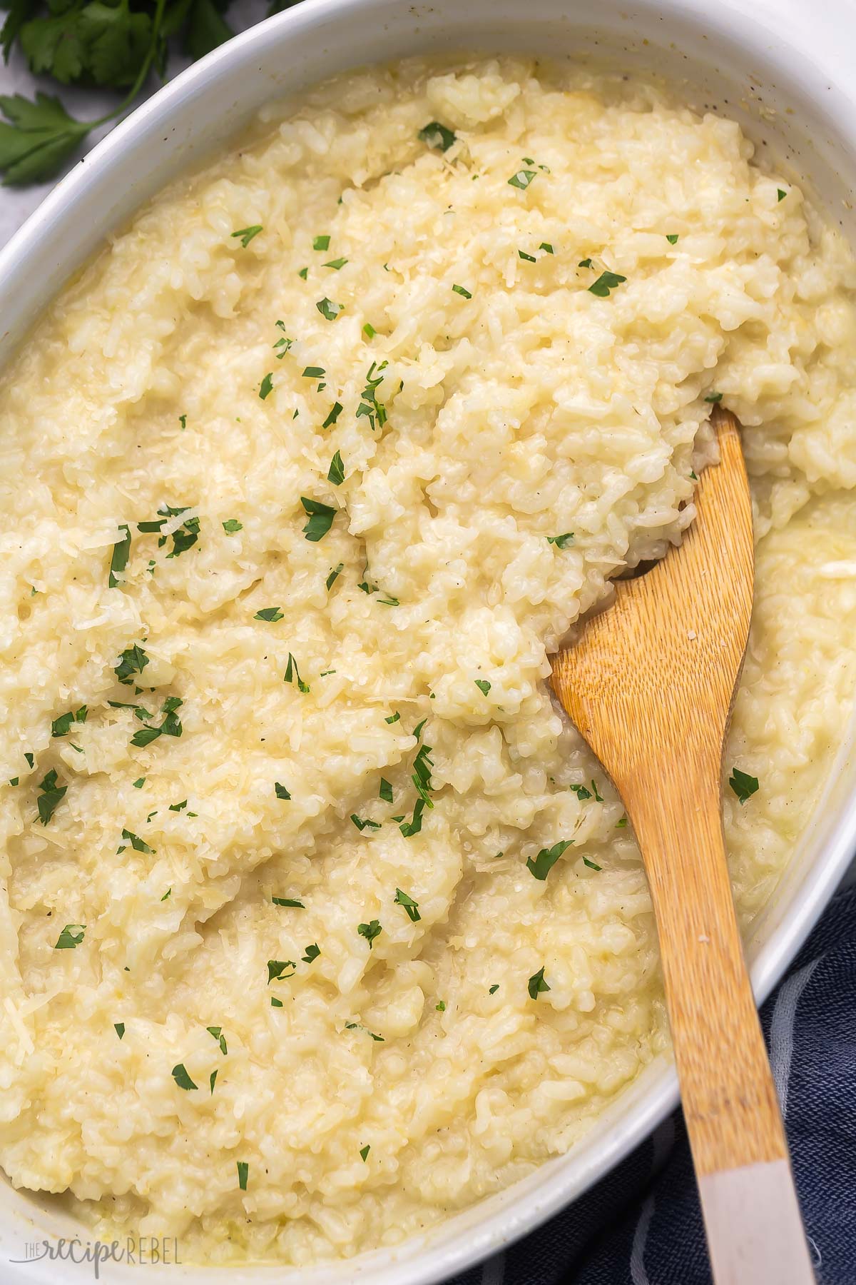 Top view of baked risotto in a casserole dish with a wooden spoon in it.