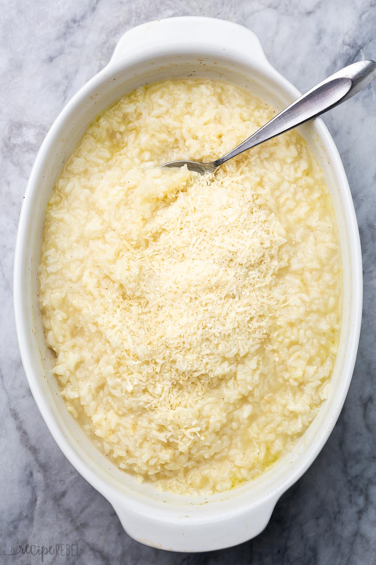 overhead view of baked risotto in a white dish with a spoon.