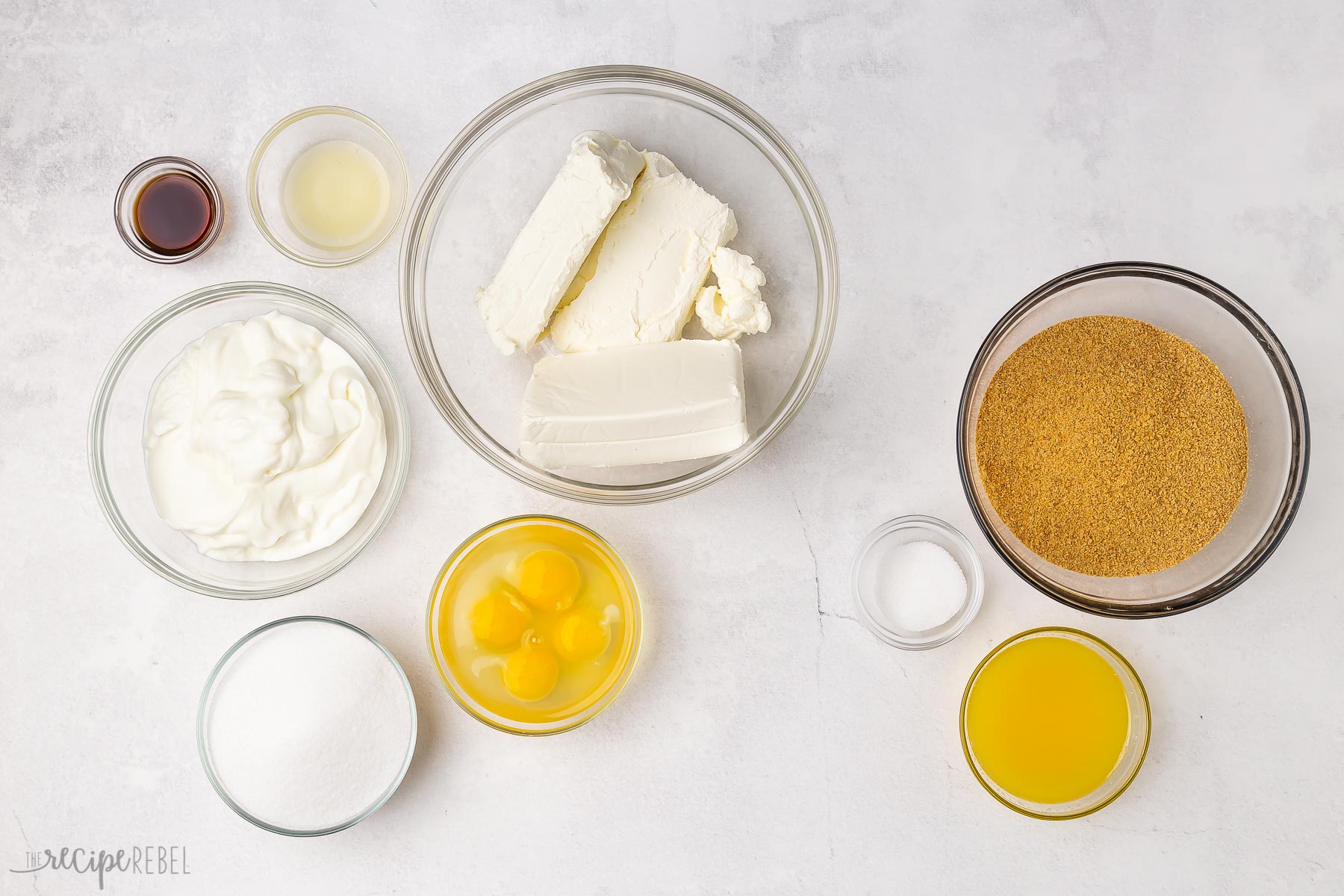 ingredients needed for baked cheesecake on white background.