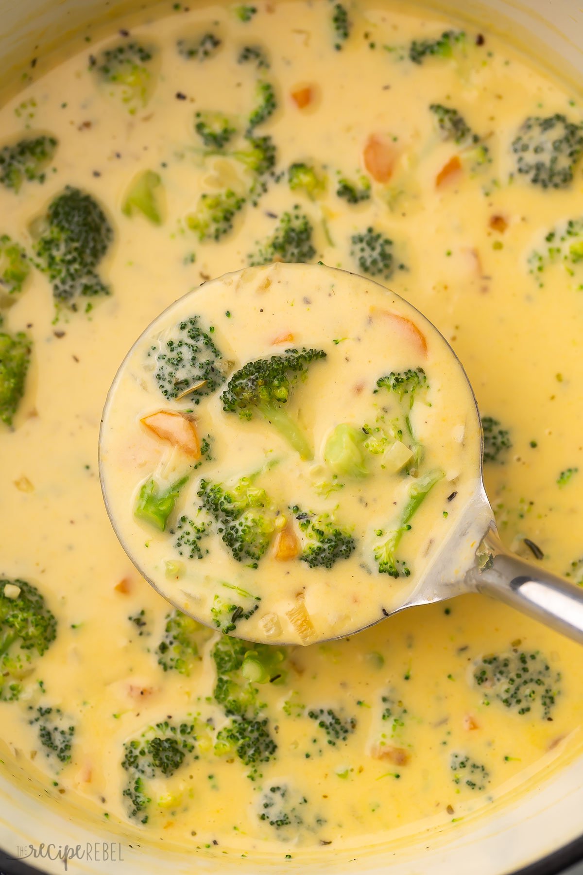 Close up of ladle of broccoli soup held over pot of soup.