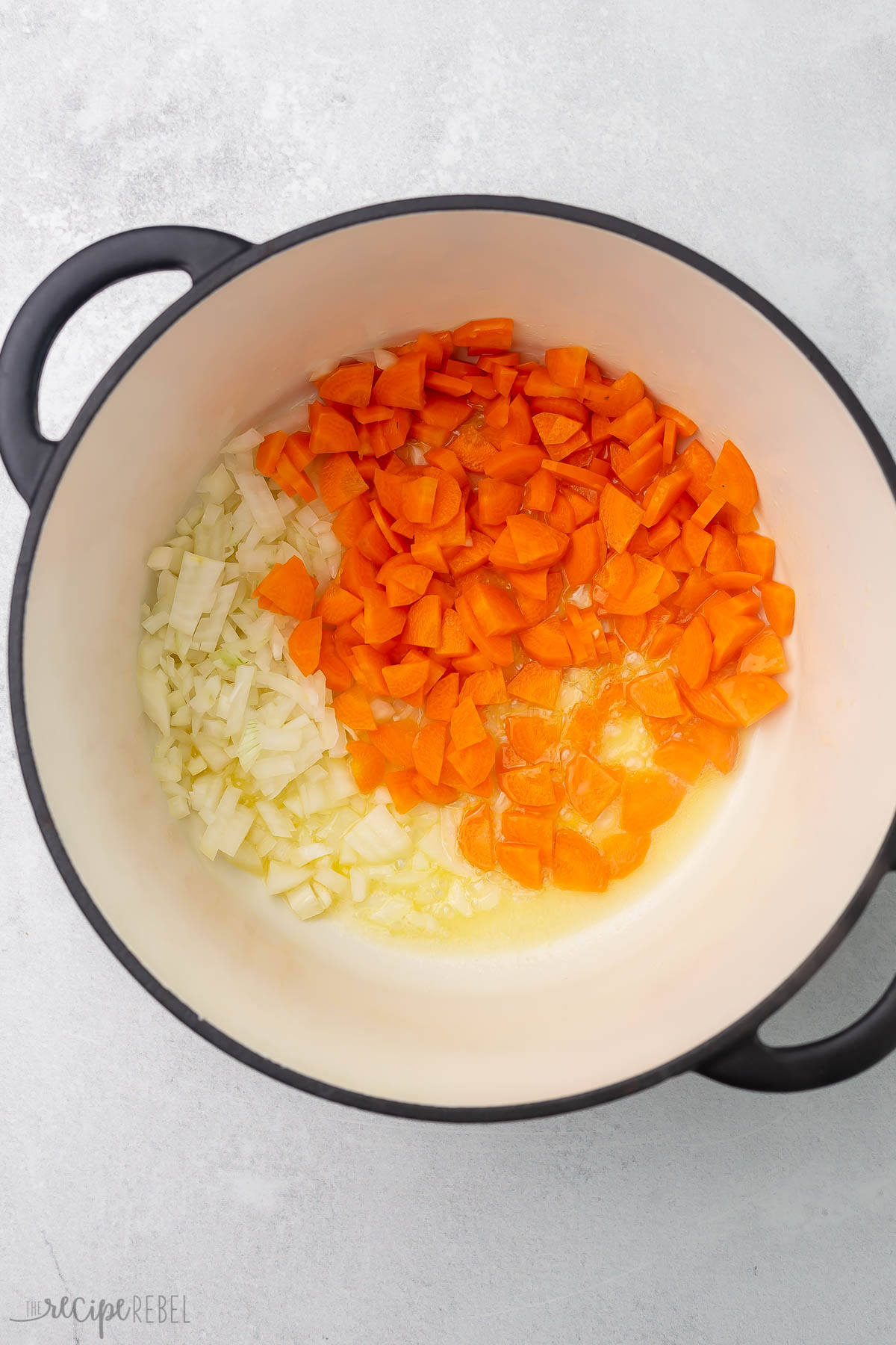 overhead view of pot with butter, carrots, and onions in it.