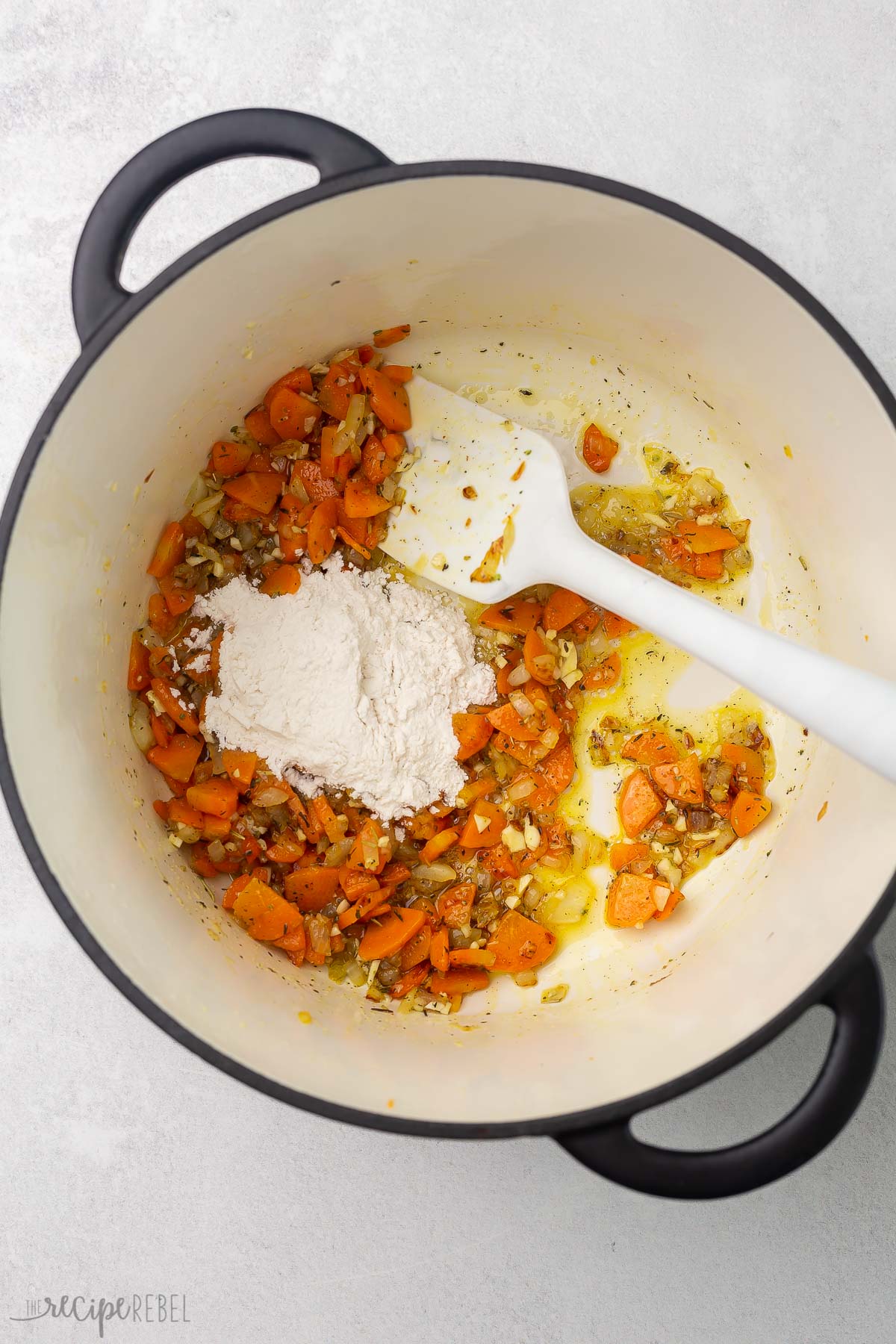 soup pot and spatula with vegetables, spices, and flour.