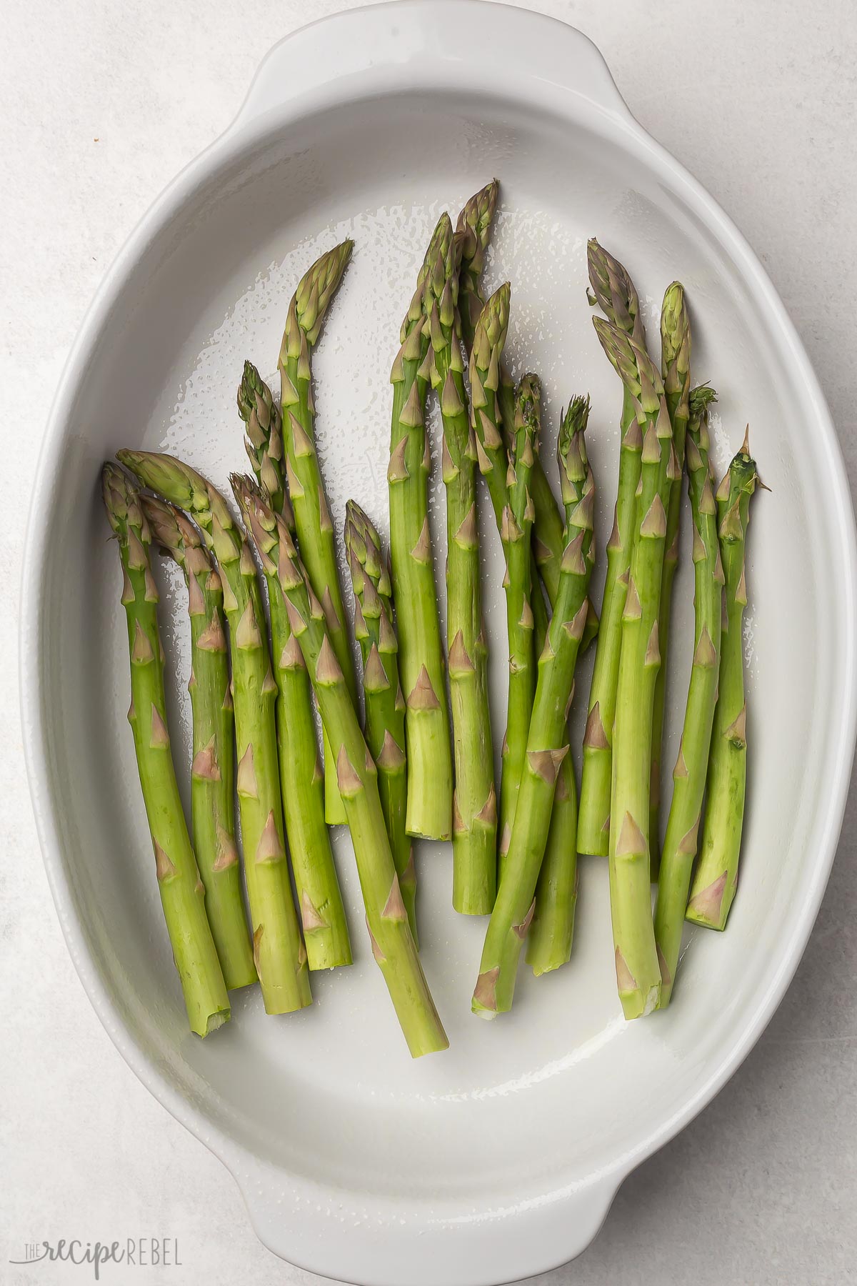 white greased dish with asparagus lying in it.