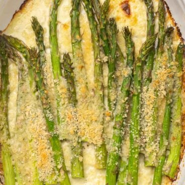 Overhead close up of baked asparagus in white dish.