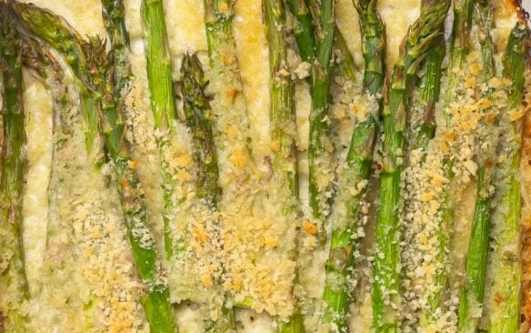 Overhead close up of baked asparagus in white dish.