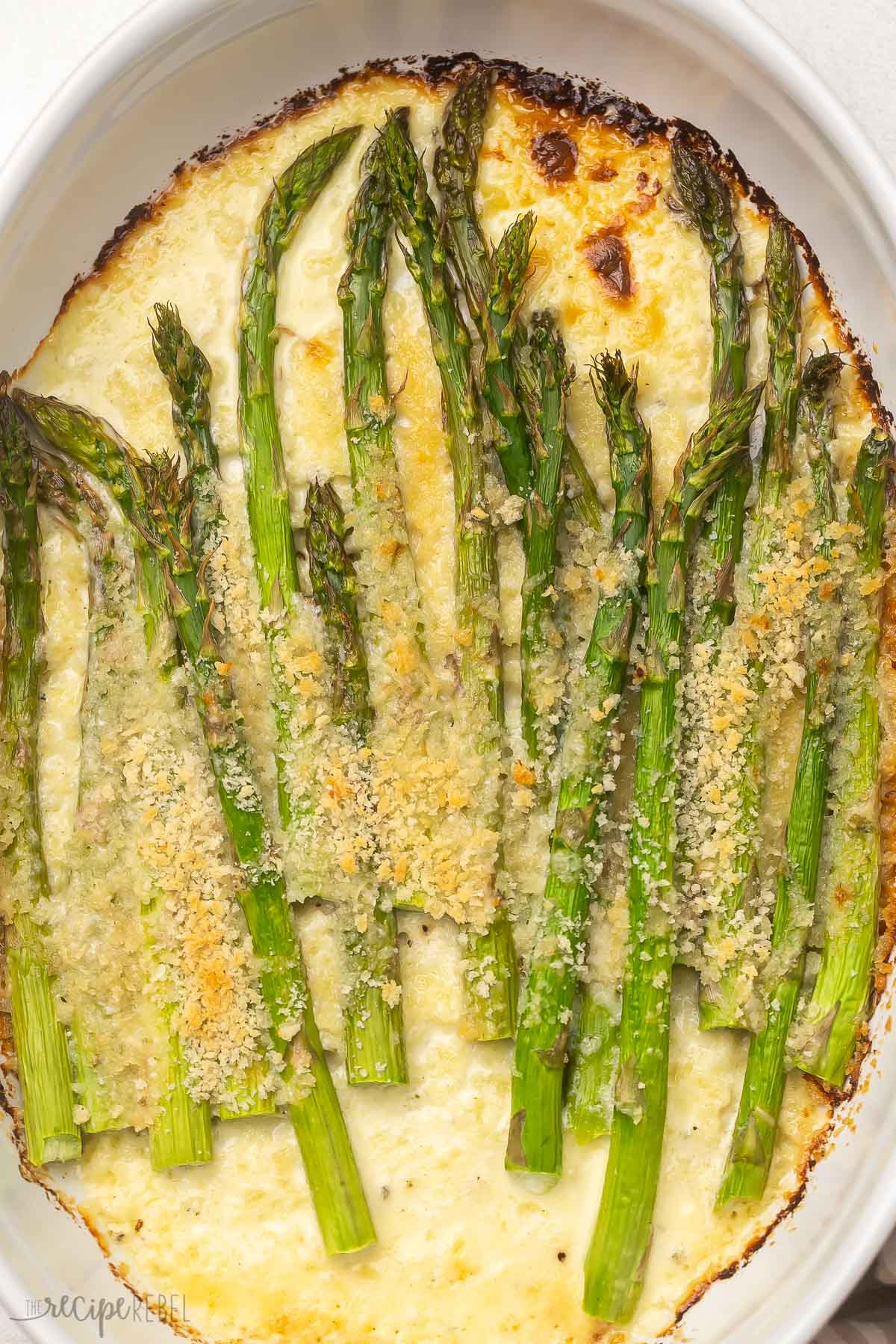 Overhead close up of baked asparagus in white dish.