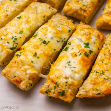 close up view of sliced cheesy garlic bread on pan.