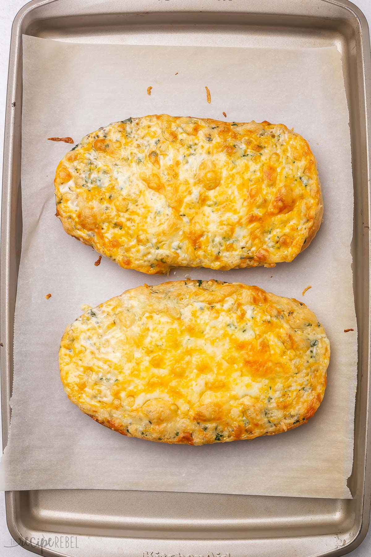 a pan with two baked loaves of cheesy garlic bread.