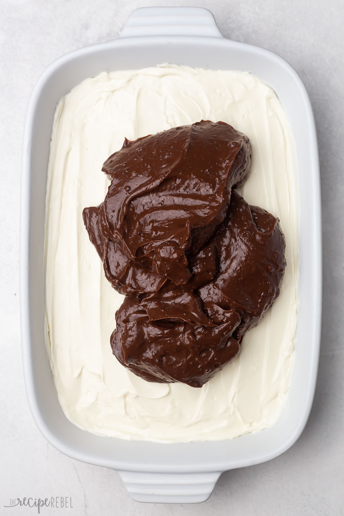 overhead shot of chocolate pudding on top of cream cheese mixture in a white pan.