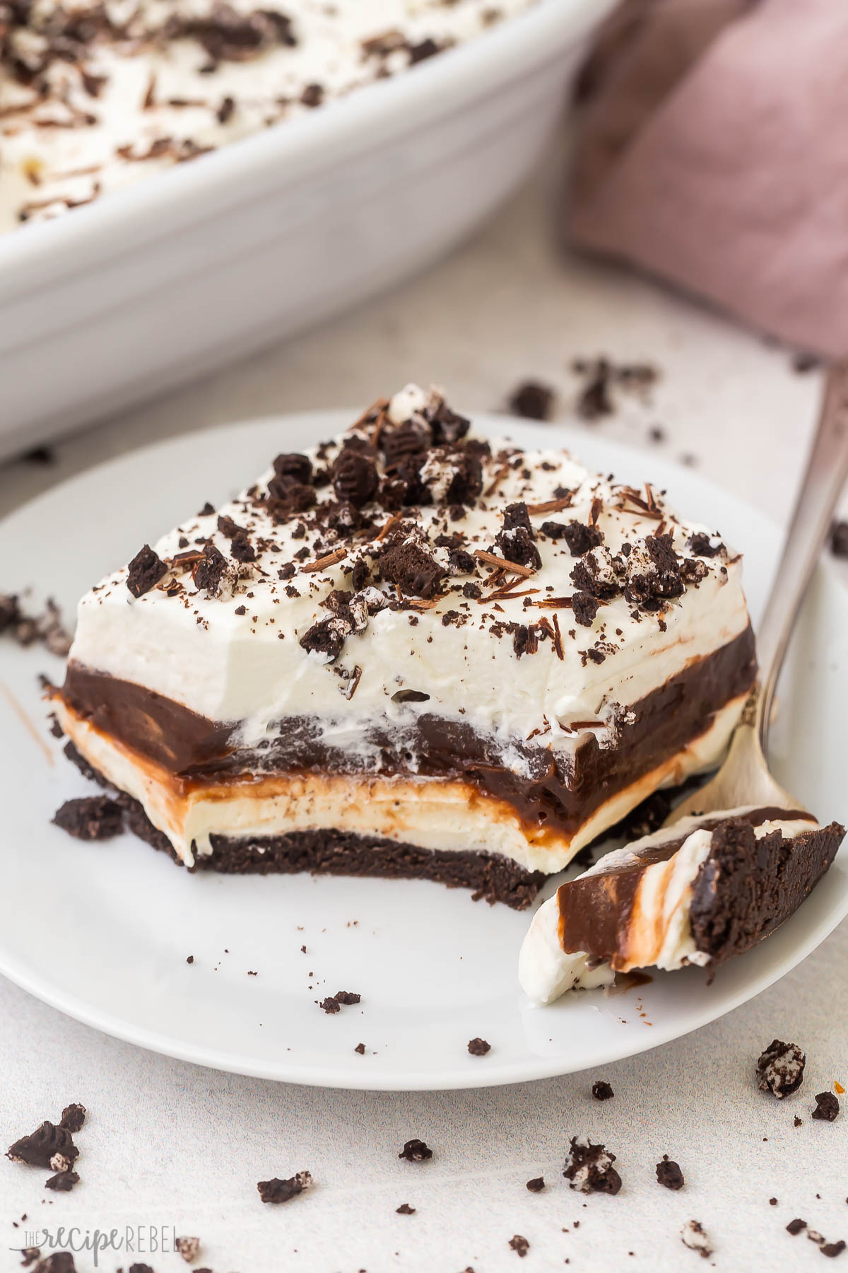 a piece of chocolate lasagna on a white plate with a fork beside it.