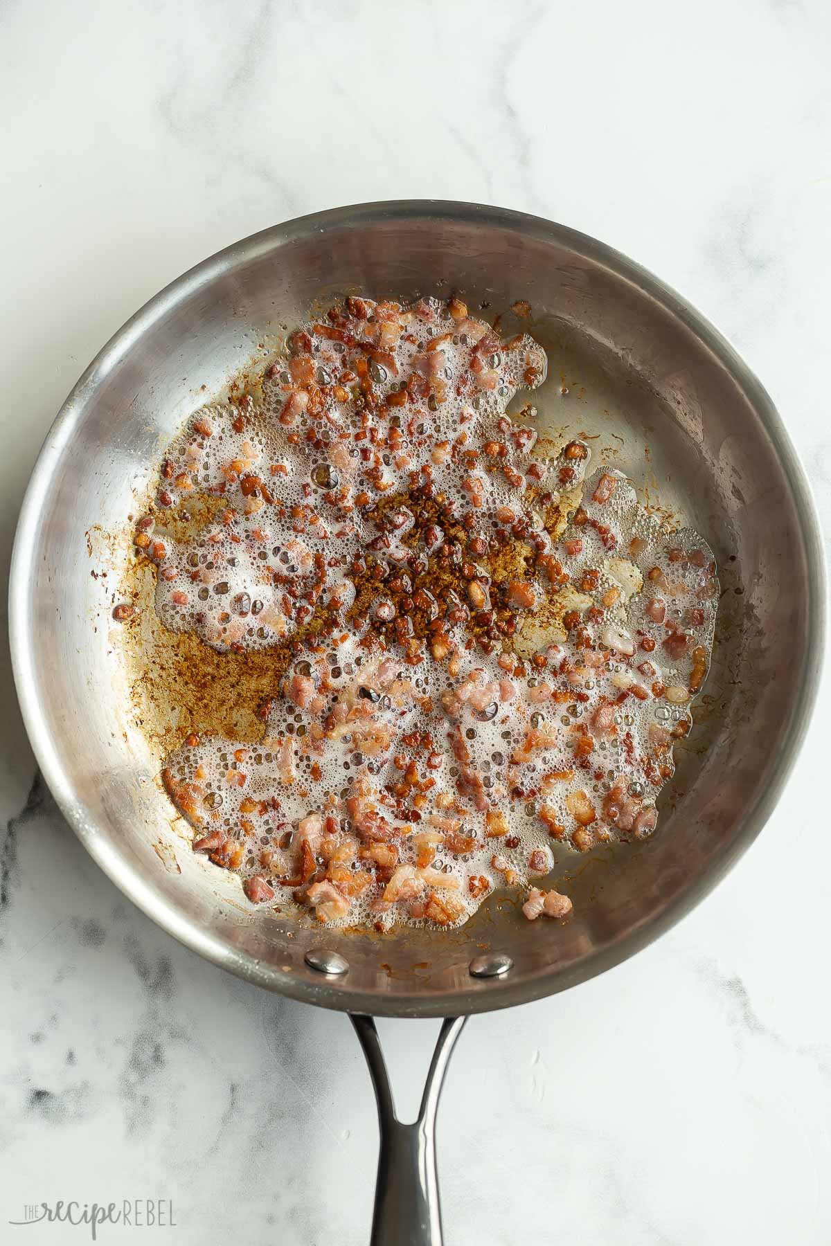 bacon browning in stainless steel skillet.