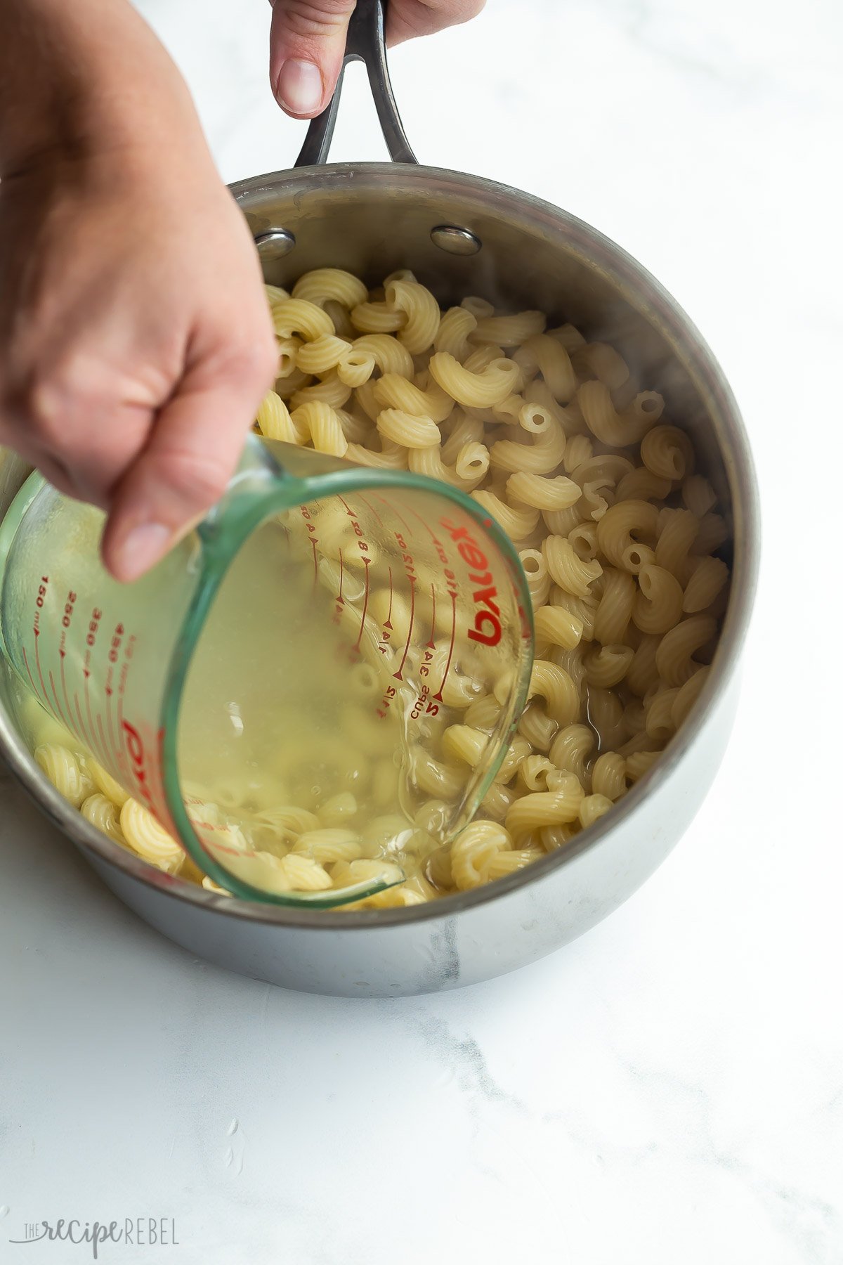 reserving pasta water with glass measuring cup.