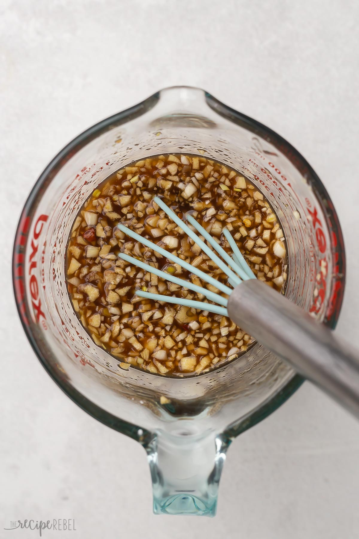 honey garlic ingredients in glass measuring cup with whisk.