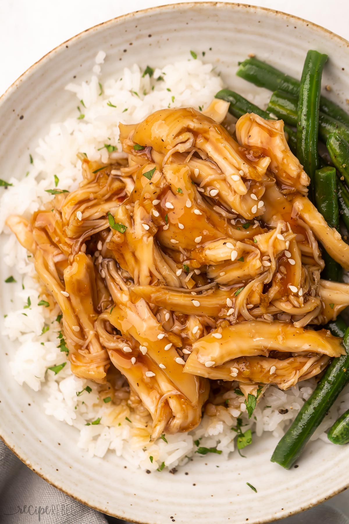 overhead close up of honey garlic chicken on rice with a side of green beans.