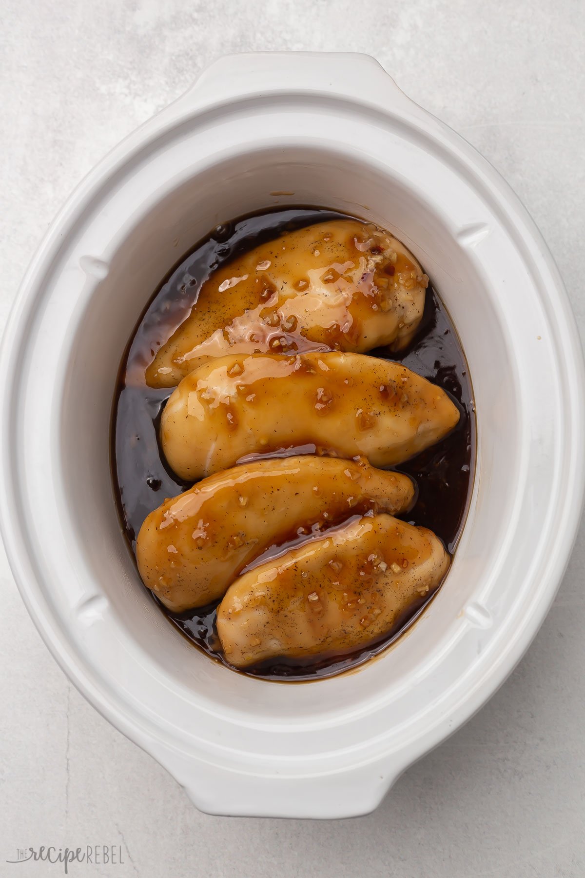 overhead shot of cooked honey garlic chicken in white crockpot.