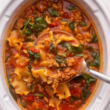 overhead view of crockpot lasagna soup with full ladle being scooped out.