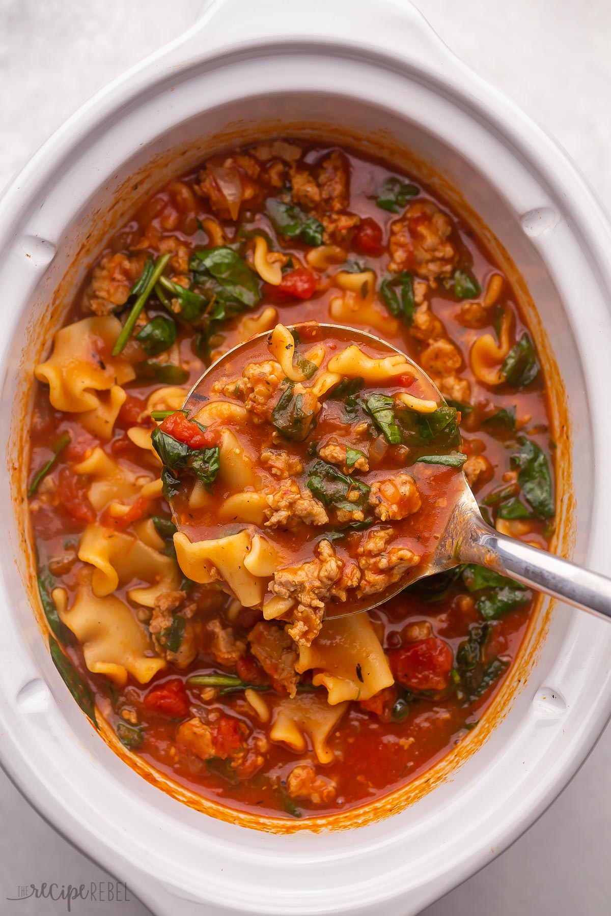 overhead view of crockpot lasagna soup with full ladle being scooped out.