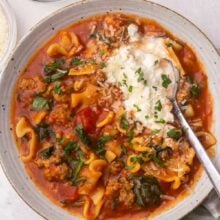 Overhead view of a full bowl of lasagna soup with a spoon in it.