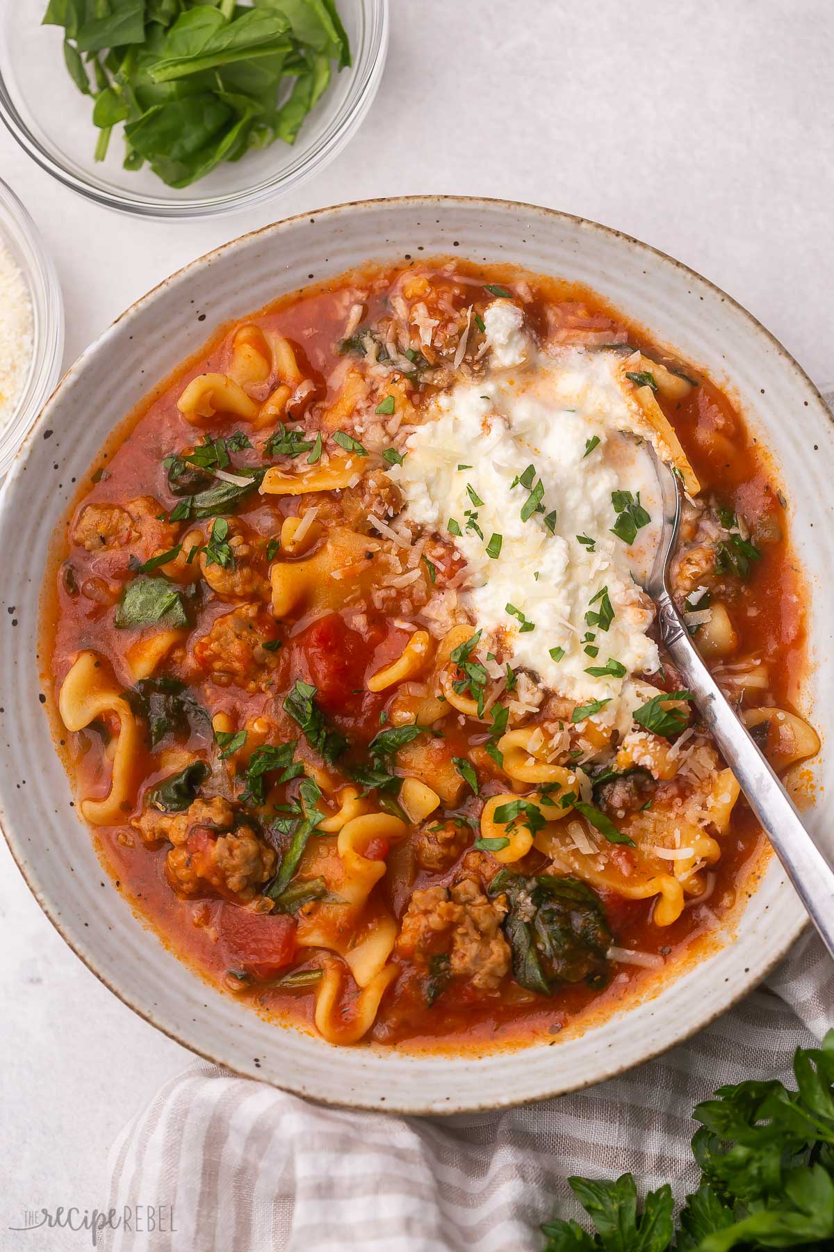 Overhead view of a full bowl of lasagna soup with a spoon in it.