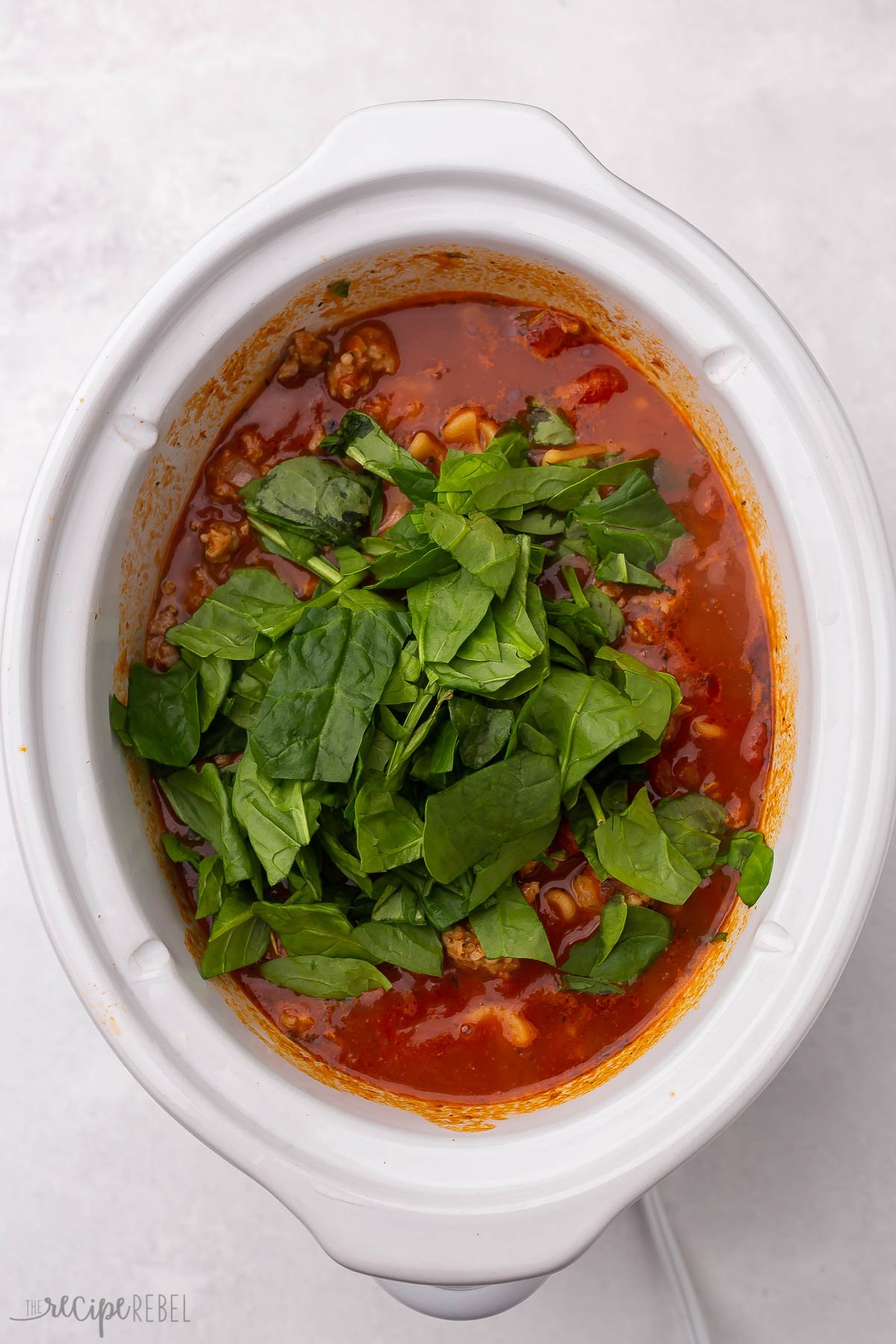 cooked lasagna soup with fresh spinach placed on top.