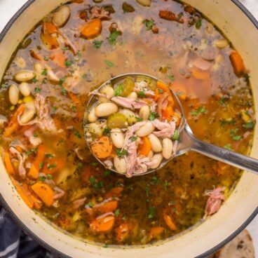 scooping ham and bean soup out of dutch oven.