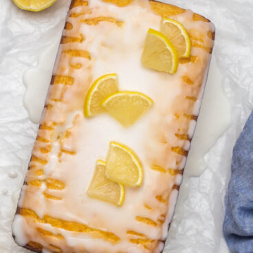 Overhead view of lemon bread loaf topped with glaze and lemon slices.