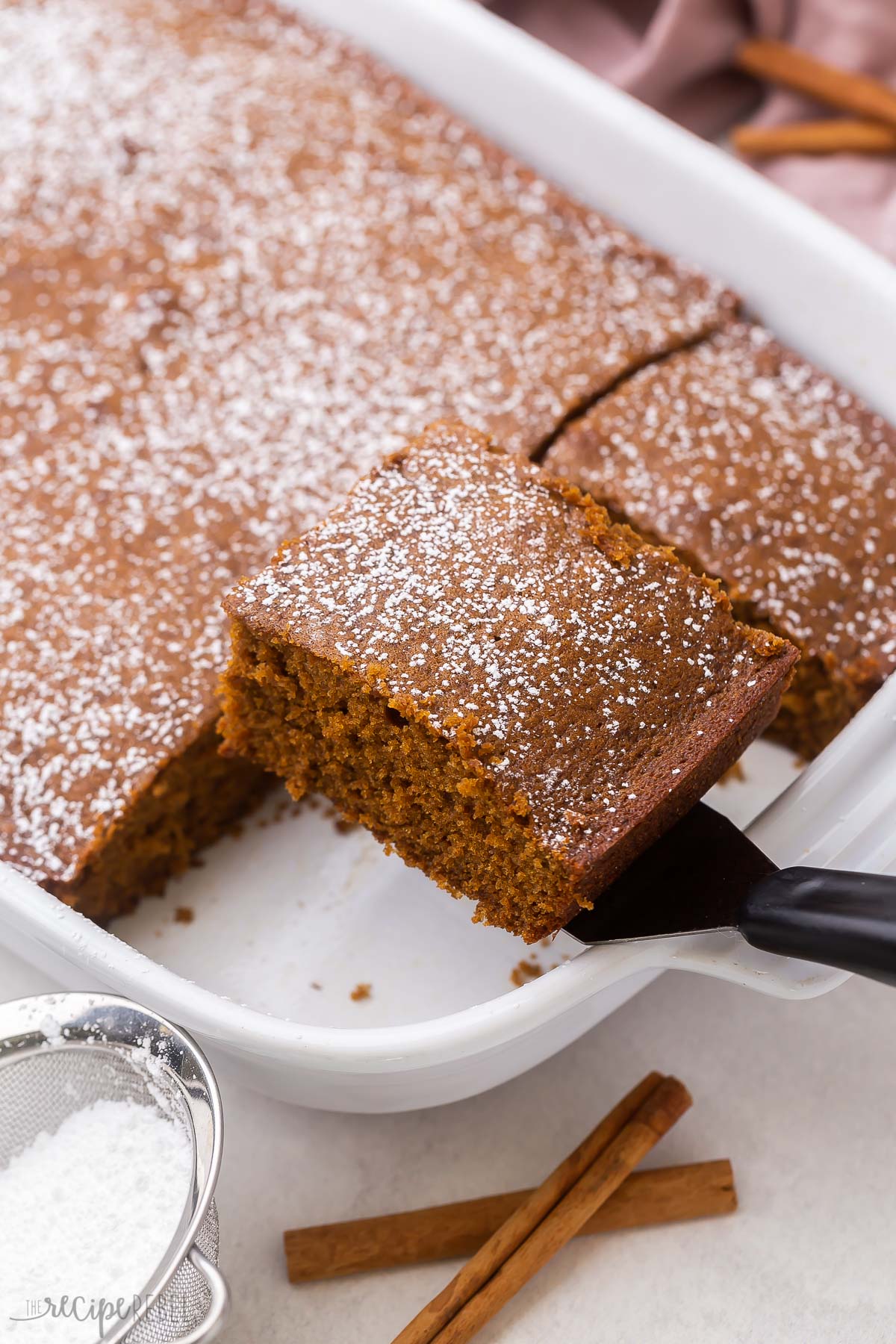 scooping a piece of gingerbread from a white pan.