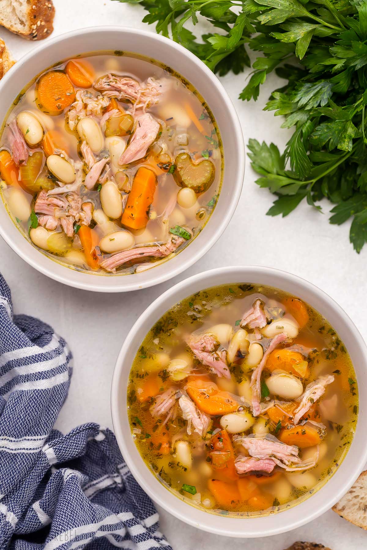 This Ham and Bean Soup is so hearty and flavorful and the perfect way to use up any leftover ham! It's loaded with veggies, ham, white kidney beans, and so much flavor. #soup #recipe | dinner recipe | dinner ideas | healthy recipe | healthy soup | healthy dinner | leftover ham two white bowls of ham and bean soup.