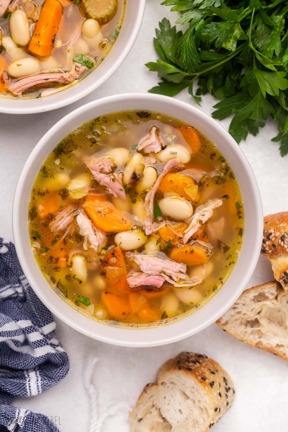 This Ham and Bean Soup is so hearty and flavorful and the perfect way to use up any leftover ham! It's loaded with veggies, ham, white kidney beans, and so much flavor. #soup #recipe | dinner recipe | dinner ideas | healthy recipe | healthy soup | healthy dinner | leftover ham a white bowl of ham and bean soup.