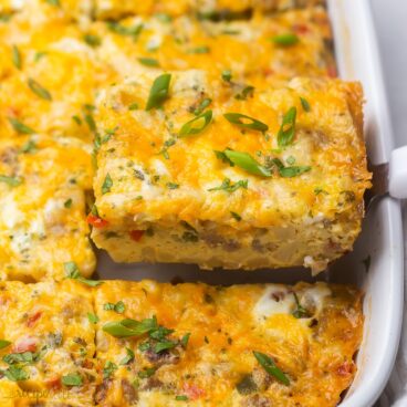 close up of a piece breakfast casserole being lifted out of white dish.